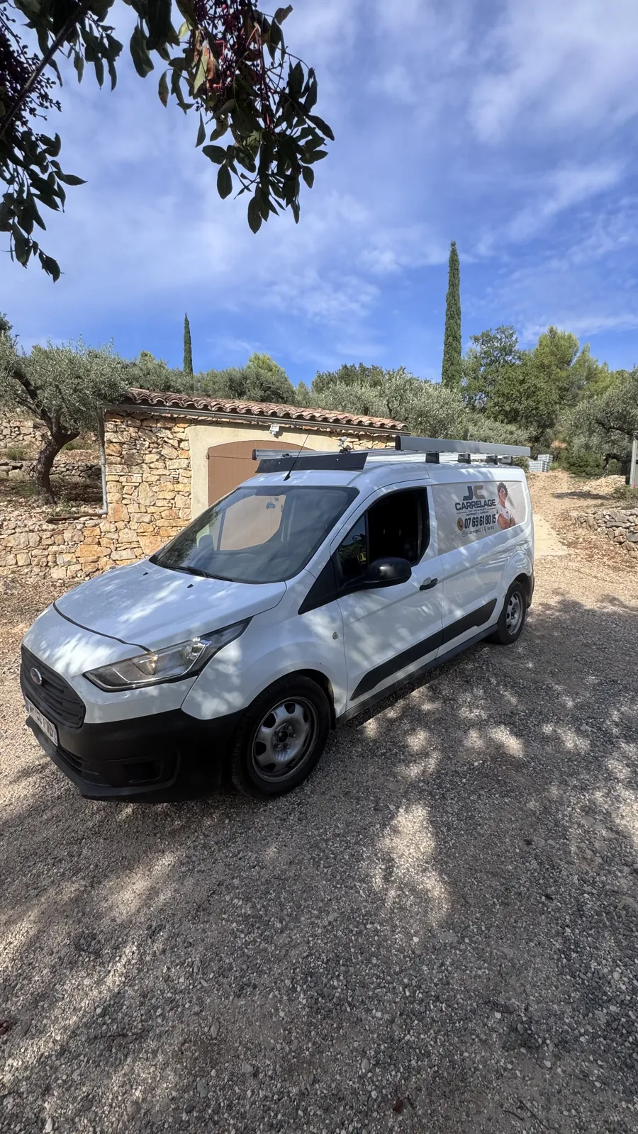 Le fourgon JC Carrelage garé devant un cabanon en pierre, entre oliviers et cyprès