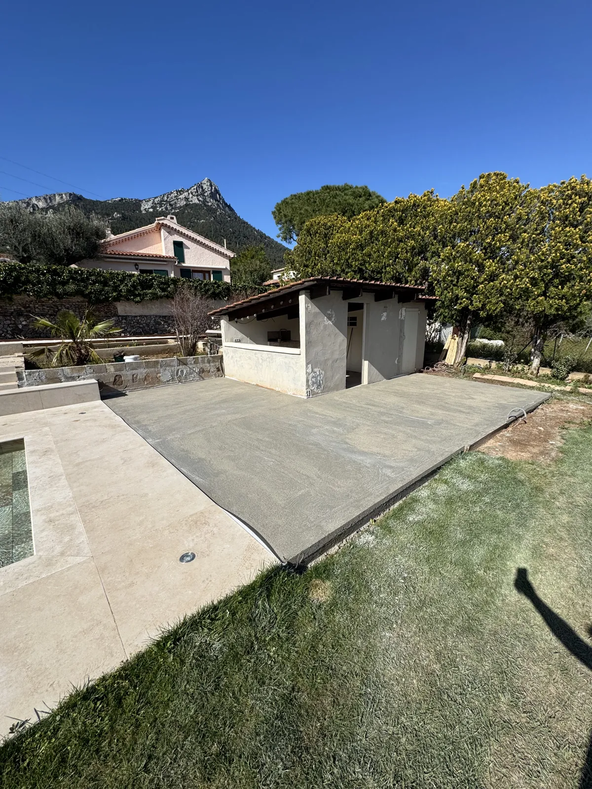 Terrasse carrelée en bordure de pelouse, massif rocheux en arrière-plan