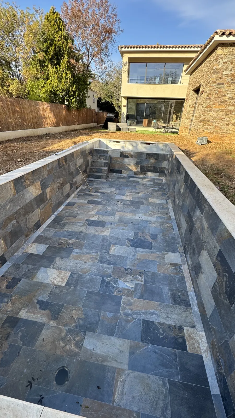 Bassin de piscine carrelé devant une villa